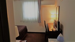 A hotel room with a bed, a desk with a computer, a lamp, and a TV. - Kuki City Hotel (Kuki)