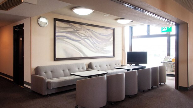 A conference room with a sofa, chairs, a TV, and a large abstract painting on the wall. - Kuki City Hotel (Kuki)