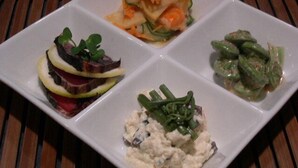 A square white plate with four different food items: a salad with greens and sliced meat, a vegetable dish with carrots and zucchini, a green vegetable dish, and a creamy dip with greens. - Mountain Inn Marodo (Iiyama)