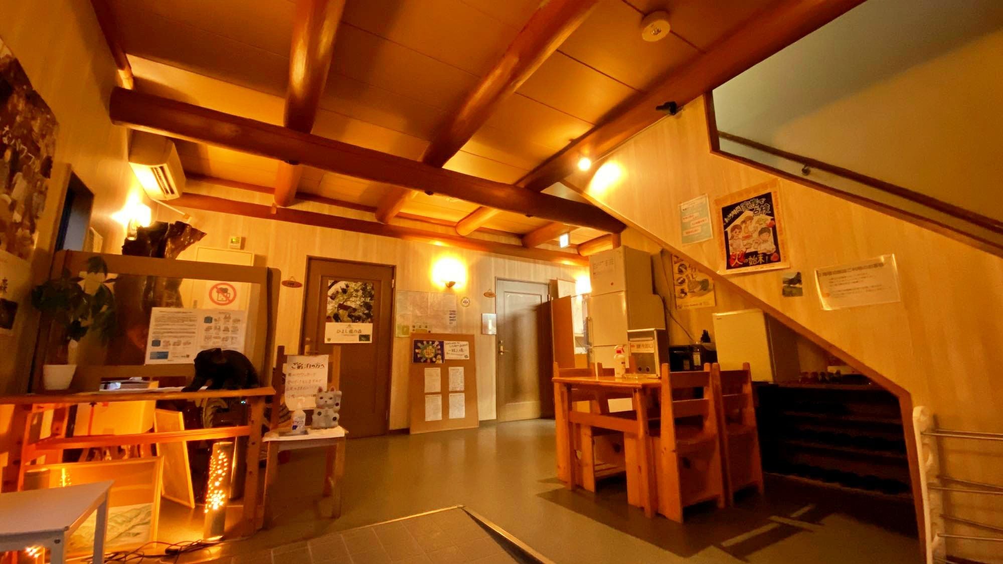 Un interior de madera con una recepción, una escalera y varios letreros y avisos en las paredes.