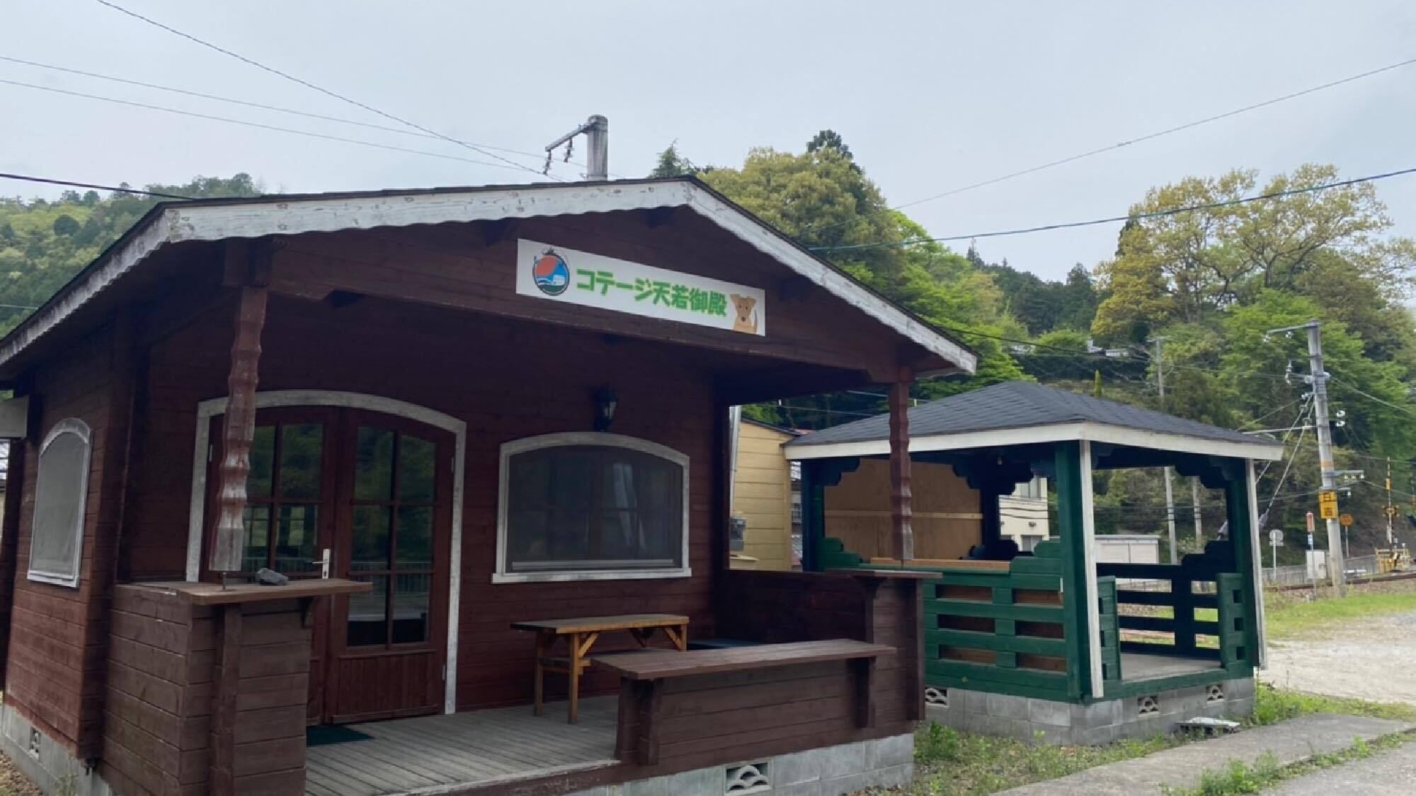 A wooden cabin with a porch, a bench, and a small table.