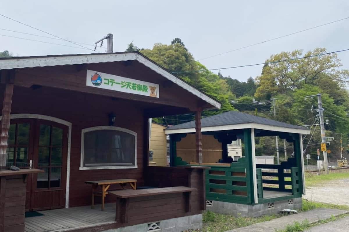 A wooden cabin with a porch, a bench, and a small table.