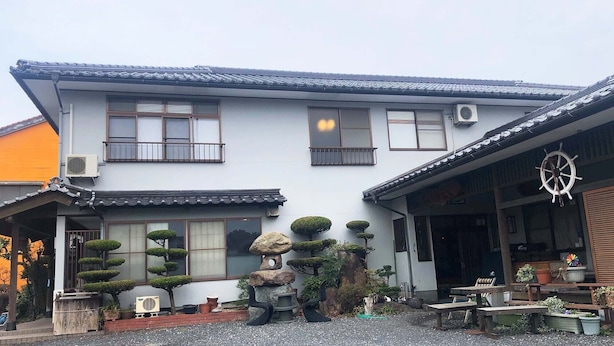A traditional Japanese house with a tiled roof, multiple windows, and a small garden with bonsai trees and a rock garden. - Otomaridokoro Nakamura <oki Shoto> (Ama)