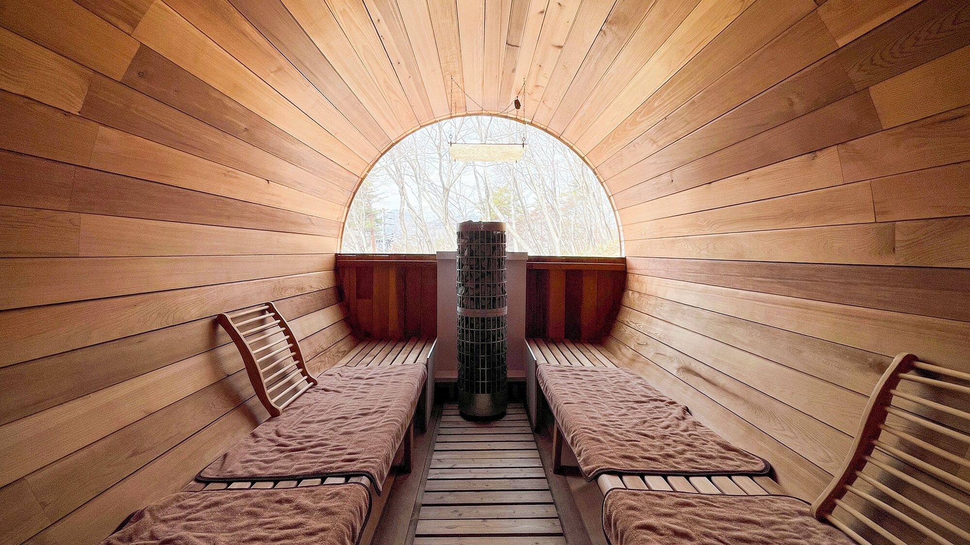 A sauna with wooden walls, benches, and a central heater.