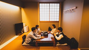 A tatami mat room with a low table, a television, and a shoji screen. - Takiyoshi Guesthouse (Tanabe)