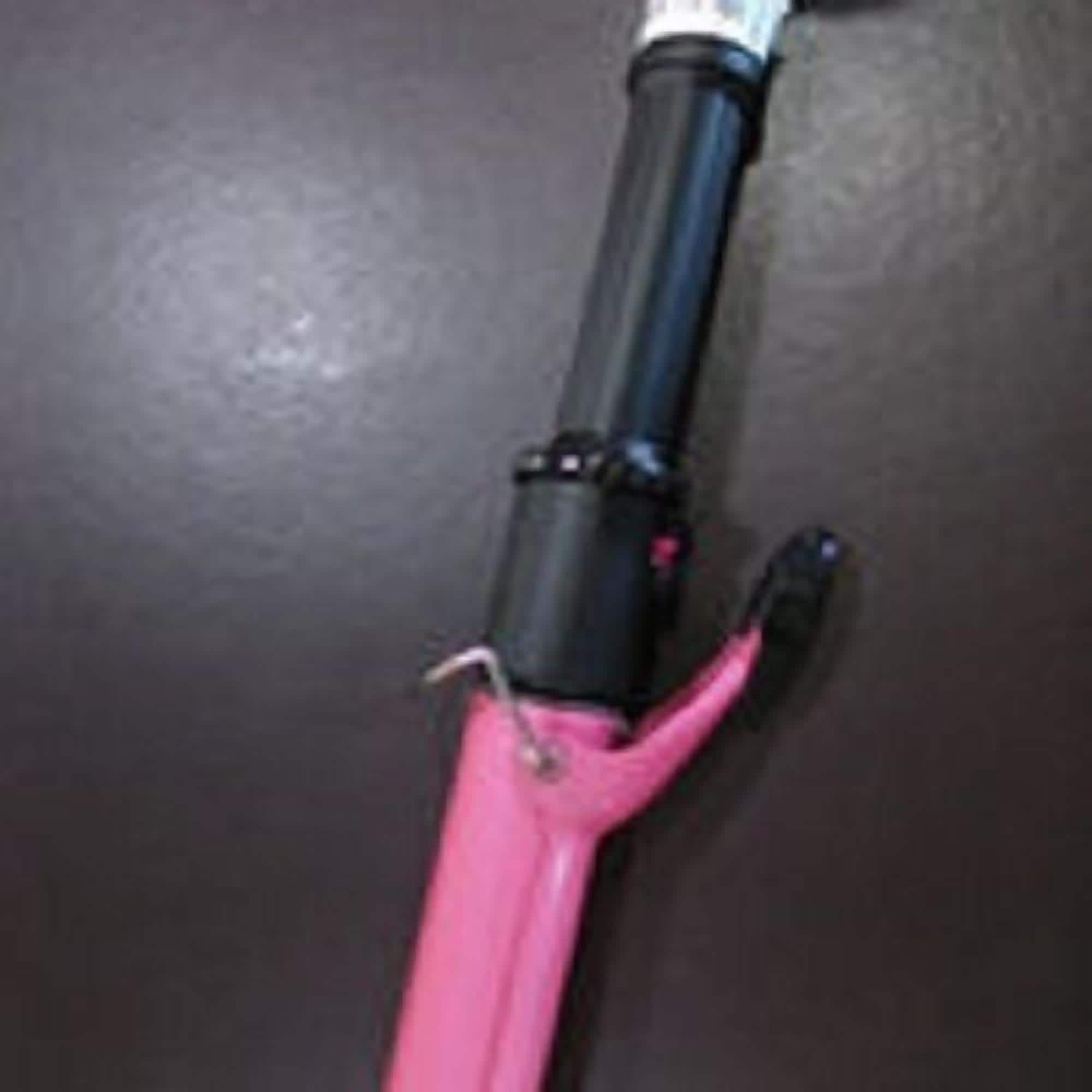 A pink and black object with a cylindrical shape and a black handle.