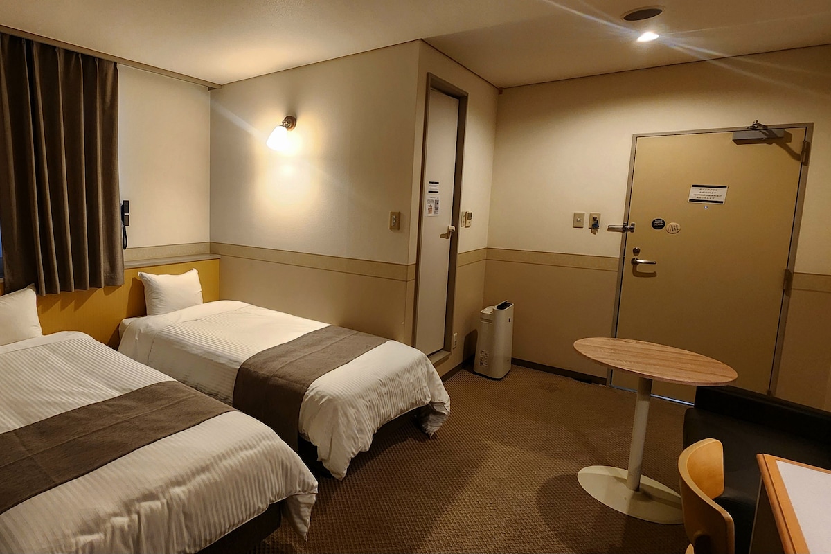 Une chambre d’hôtel avec deux lits, une petite table et une chaise.