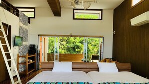 Un dormitorio con una cama grande, un televisor, una escalera y vistas a la vegetación a través de una puerta corredera.