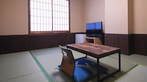 A traditional Japanese room with tatami flooring, a low table, a television, and a futon bed. - Business Hotel Wayokan/annex Wako (Inazawa)