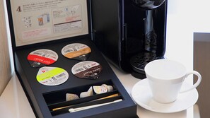 A coffee machine with a manual, a box of coffee pods, and a cup and saucer on a table. - Business Hotel Wayokan/annex Wako (Inazawa)