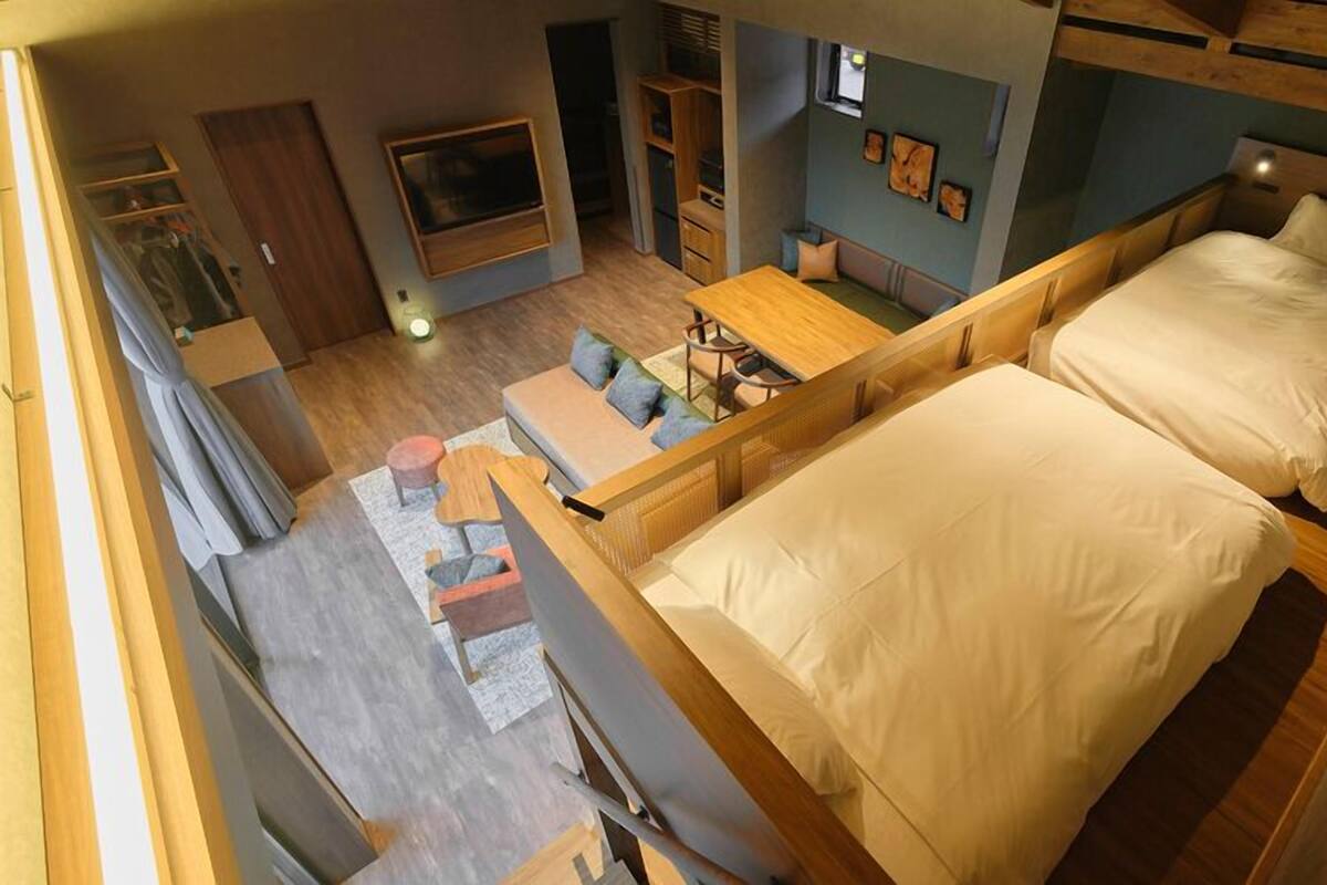 A loft-style bedroom with a large bed, a desk, and a seating area.