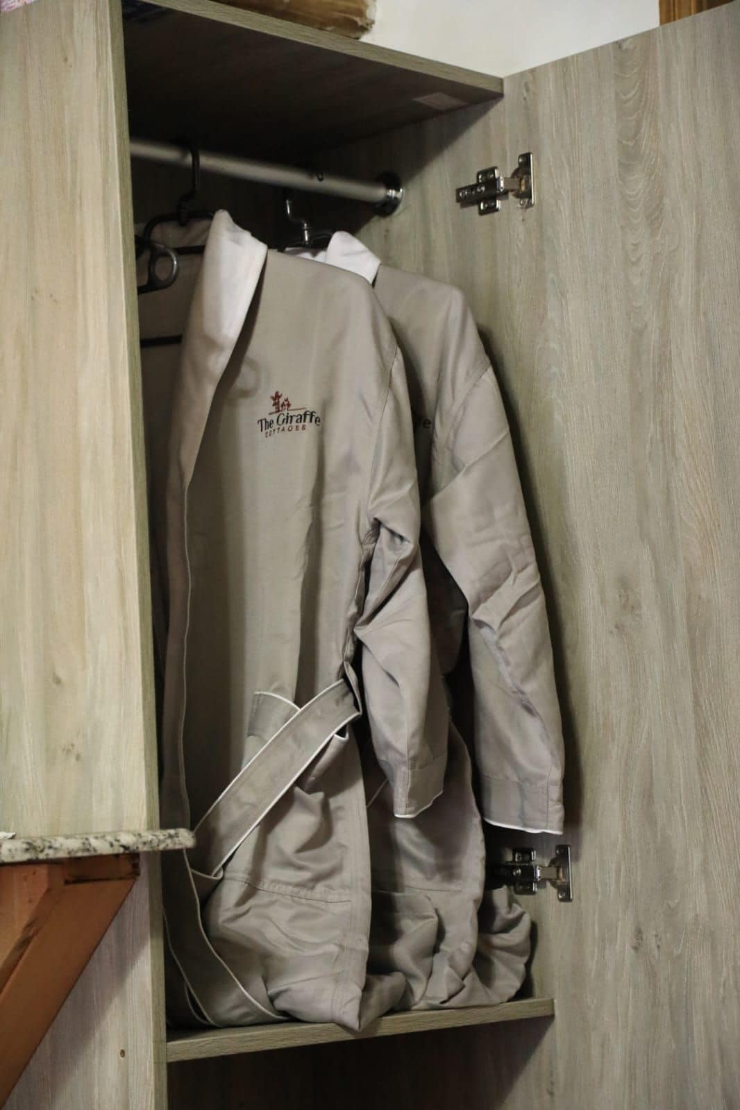 A wooden wardrobe with a hanging garment labeled 'The Giraffe Contadoes.'