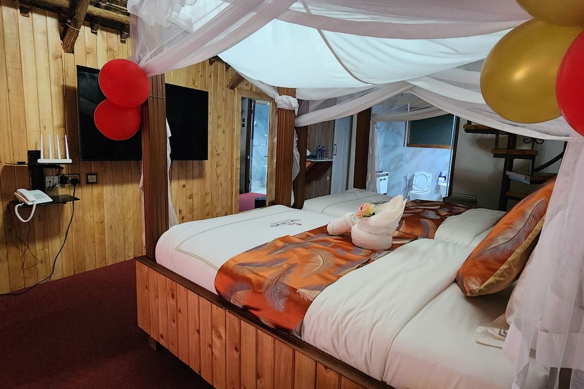 Ein Zimmer mit Holzwänden, einem Bett, einem Fernseher und einem Gemälde an der Wand.