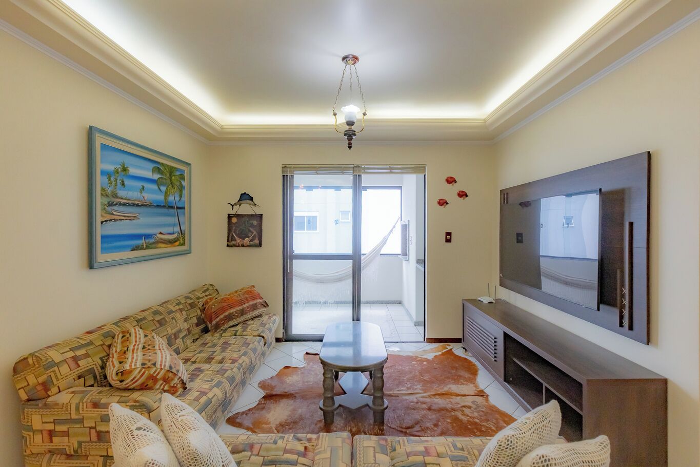 A living room with a sofa, a coffee table, a TV, and a large window.