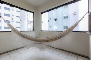 Ein Zimmer mit einer Hängematte, großen Fenstern und Blick auf ein Gebäude.