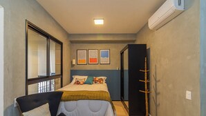 Ein Schlafzimmer mit Bett, Stuhl, Kleiderhaken und Fenster.