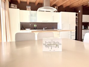 Eine moderne Küche mit weißen Schränken, einer Spüle und einem Essbereich mit Tisch und Stühlen.