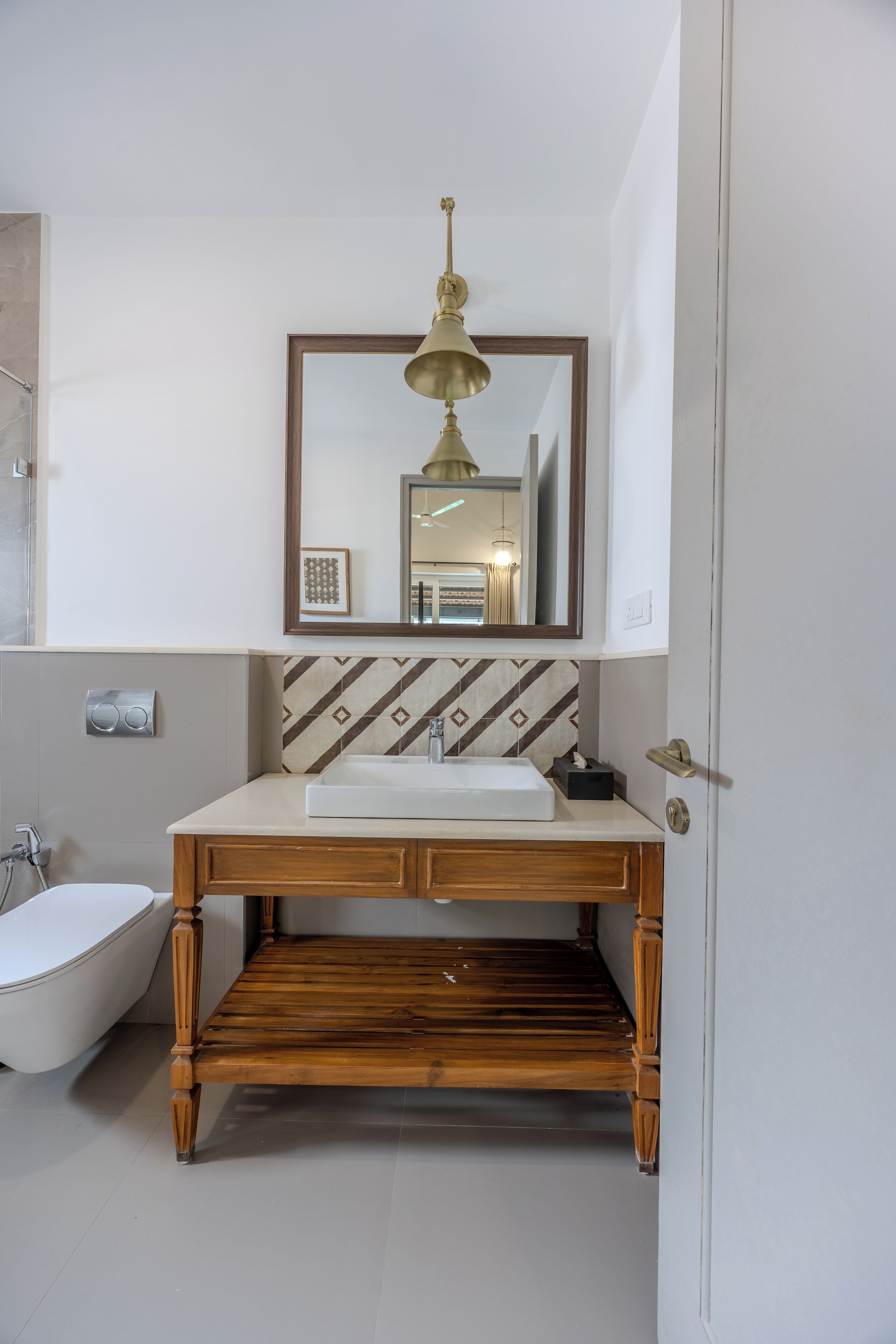 A bathroom with a wooden vanity, a sink, a mirror, and a shower.