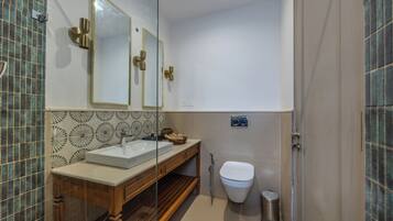 Une salle de bain avec un meuble-lavabo en bois, un lavabo blanc, un miroir avec un cadre doré, des toilettes blanches et une poubelle.