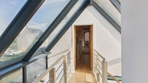 A modern interior with a sloped glass roof, wooden flooring, and a view through a doorway. - Beautiful house for 8 with garden – Sea view (Penmarch)