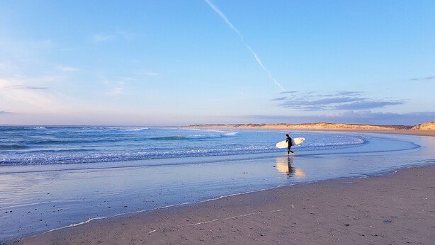 A beach with a person carrying a surfboard. - Beautiful house for 8 with garden – Sea view (Penmarch)