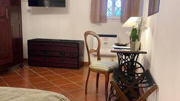 Un dormitorio con cama, armario de madera, televisor, escritorio con lámpara y ventana con cortinas.