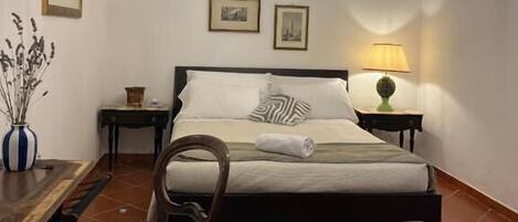Un dormitorio con cama, una silla, una mesa, una lámpara y un candelabro.