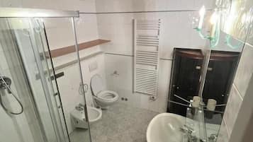 A compact bathroom with a glass shower enclosure, a white sink, and a toilet.
