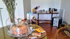 A dining table with food, a vase of flowers, and a kitchen in the background. - Levante Camere (Calderara di Reno)