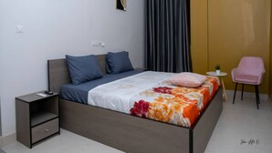 A bedroom with a bed, a nightstand, a chair, and an air conditioning unit. - Maison Recla (Lomé)