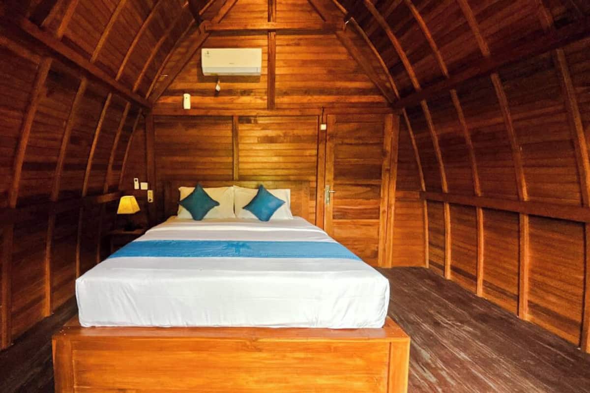 A cozy, wooden-paneled room with a bed, a nightstand, and a lamp.