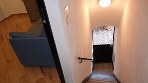 A staircase with a wooden floor leading to a landing with a patterned wall and a small window. - Cà DE SAN SCì (Sanremo)
