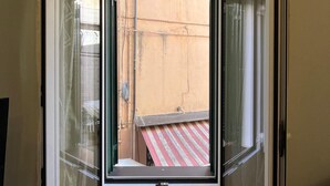 A room with a corner window, a small table, and a plant. - Cà DE SAN SCì (Sanremo)