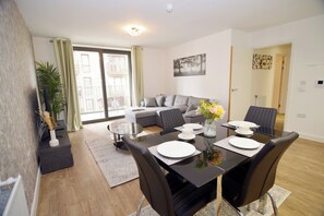 A modern living room with a dining area, a sofa, and a large window with curtains. - Apartment - Sleeps 4 - Spacious City Base, Wifi (London)