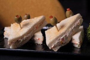 Ein Sandwich mit Oliven auf einem schwarzen Teller.