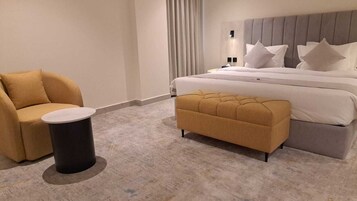 A hotel room with a bed, a sofa, a small table, and a bench.
