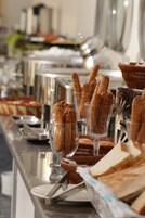A buffet setup with bread and pastries in clear glass containers.