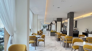 Un restaurant moderne avec des chaises jaunes, un sol en marbre et une vue sur la ville.