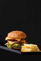 Una hamburguesa con papas fritas sobre un plato negro.
