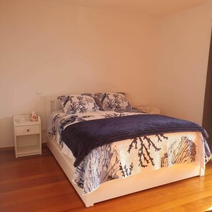 A bedroom with a bed, a nightstand, and a wooden floor. - Oceanview Gateway 
Beautiful 2Bed/2Bath Apartment (Caniço)
