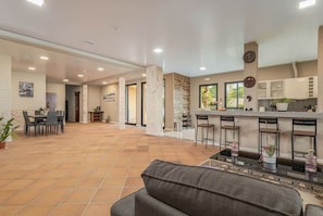 A spacious indoor area with a dining table and chairs, a kitchen with a bar, and a seating area with a sofa. - Suite 8 - Private Veranda with Ocean View (Gaula)