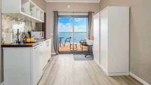 Eine kleine Küche mit Blick auf einen Balkon, einem Essbereich und einem weißen Kleiderschrank.