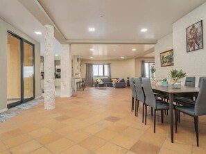 A spacious living area with a dining table, chairs, and a sofa.