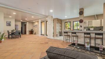 A spacious indoor area with a dining table and chairs, a kitchen with a bar, and a seating area with a sofa.