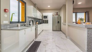 A modern kitchen with white cabinets, a stainless steel refrigerator, and a large window. - Suite 7 -
Private veranda with ocean view (Gaula)