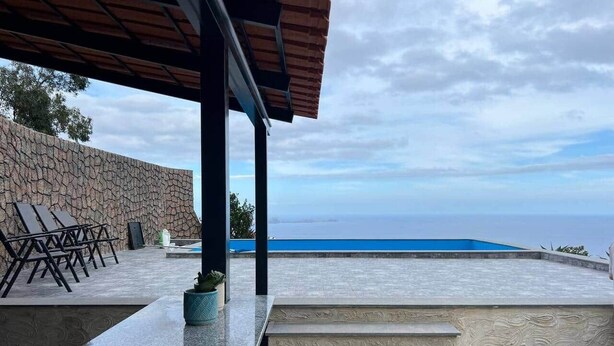 A poolside area with steps leading to a pool, lounge chairs, and a stone wall. - Suite 7 -
Private veranda with ocean view (Gaula)