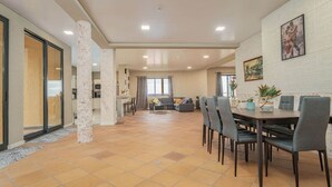 A spacious living area with a dining table, chairs, and a sofa. There is a kitchen in the background and a large window providing natural light. - Suite 7 -
Private veranda with ocean view (Gaula)