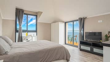 Ein modernes Hotelzimmer mit Bett, Schreibtisch, Fernseher und einem Balkon mit Blick.