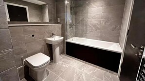 Et moderne badeværelse med toilet, vask og badekar.