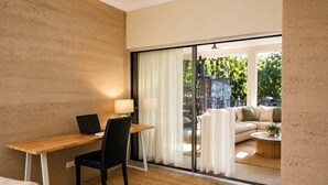 A modern room with a wooden desk, a chair, a laptop, a lamp, and a sofa with a view of the outdoors. - Fishers Villa (Crescent Head)